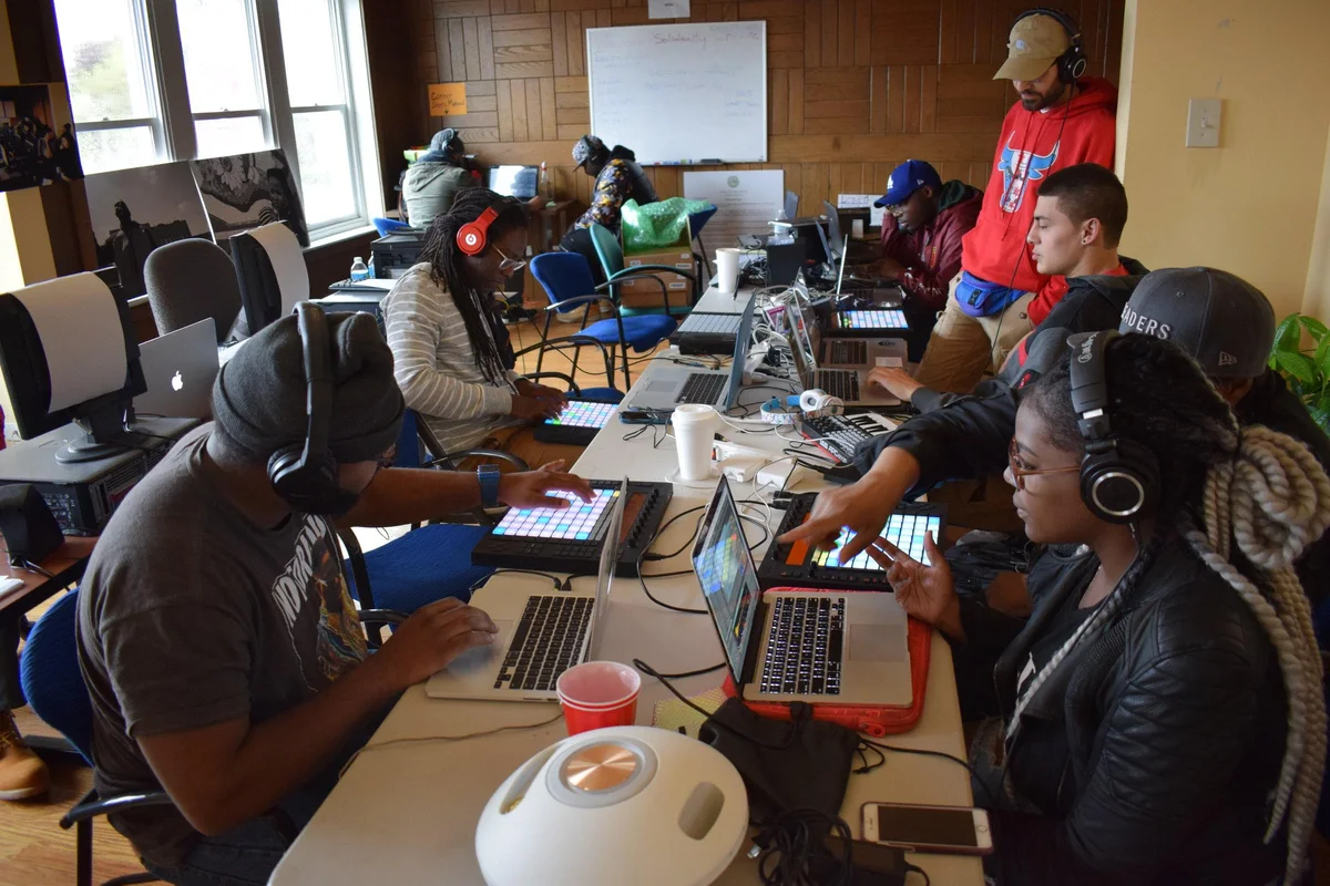 Producers working together with laptops and headphones in a group workshop